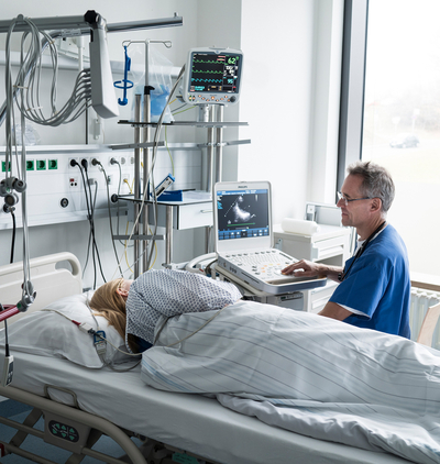 Bild Siloah St. Trudpert Klinikum, Chest Pain Unit, Chefarzt sitzt an Patientenbett und überwacht die Funktionen 