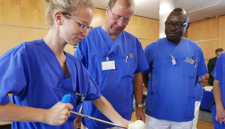 Praktische Jahr am Siloah St. Trudpert Klinikum, Foto von Praktikantin bei der Arbeit an einem Knochenmodell, zwei Ärzte schauen zu und erklären.