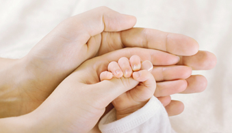 Bild Siloah St. Trudpert Klinikum, Geburtsklinik, Nach der Entbindung, zu sehen sind drei Hände, die ineinander liegen, untern ist die Hand des Vaters, darauf die der Mutter und in Ihrer liegt die kleine Hand des Neugeborenen 